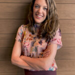 Core Collaborative Partner Consultant, Kristen Widmer portrait shot, arms folded, leaning against wall.
